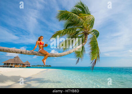 Maldives, Rangali Island. Conrad Hilton Resort. Woman in palm tree at the white sand beach. (MR) Stock Photo