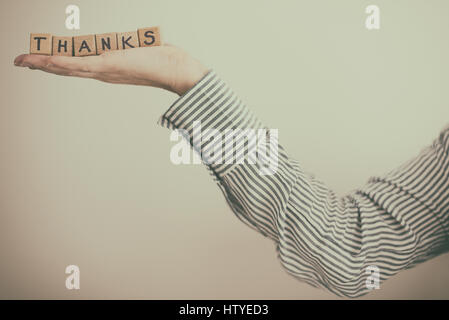 woman's Hand holding wooden building blocks spelling word Thanks Stock Photo