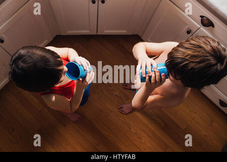 Boy and girl standing in kitchen drinking water Stock Photo