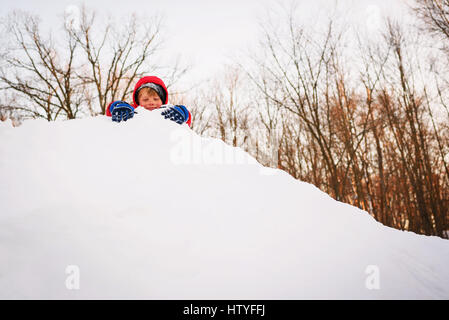 Boy playing on top of a pile of snow Stock Photo