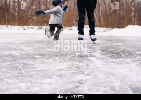 Boy learning to ice skate with his father Stock Photo