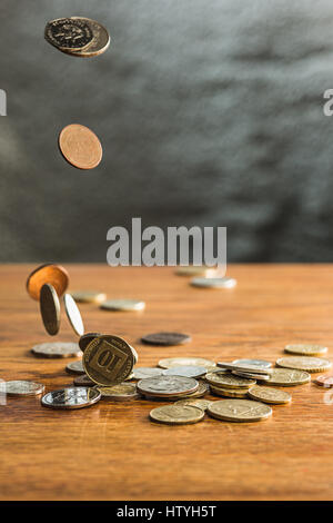 Magnifying glass with gold and silver coins on white background