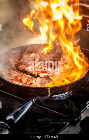 Fire at the pan on stove while chef is cooking Stock Photo