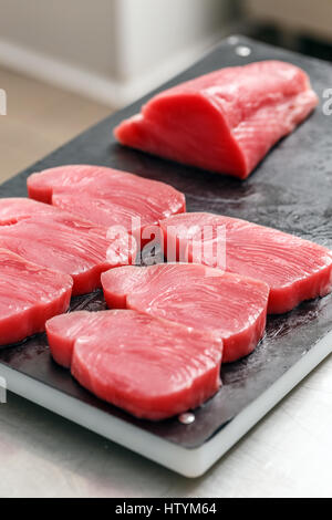 Raw tuna steak on black cutting board Stock Photo