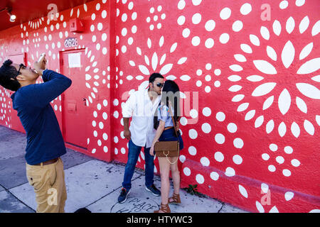 Miami Florida,Wynwood,urban graffiti,street art,painted wall mural,Hispanic woman female women,man men male,couple,kissing,picture,smartphone cell pho Stock Photo