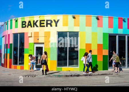 Florida South,Miami,Wynwood,urban graffiti,street art artwork,painted wall mural,Zak the Baker BAKERY,building,exterior,entrance,colorful,store,couple Stock Photo