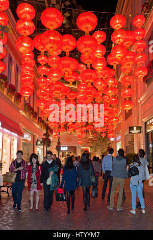 Local people and tourists walking along a street in Hong Kong with traditional Chinese lanterns decorations hanging up celebrating New Year. Stock Photo