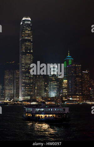 A cityscape view of the buildings along Hong Kong Island with a Star Ferry in the foreground at night. Stock Photo