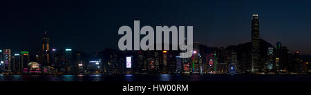 A 4 picture stitch panoramic colourful cityscape view of the buildings along Hong Kong Island from the Kowloon Public Pier at night. Stock Photo
