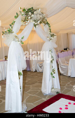 Wedding arch decorated with veil and white roses. Stock Photo