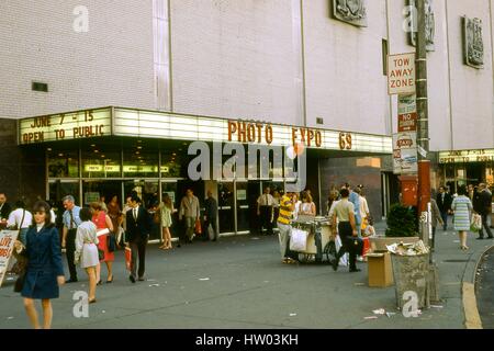 View of people walking outside of the New York Coliseum convention center, at Columbus Circle and 58th Street, on the west side of Manhattan, New York City, June, 1969. Marquee signs at the entrance advertise the 1969 Photo Expo taking place from June 7 to 15. Stock Photo