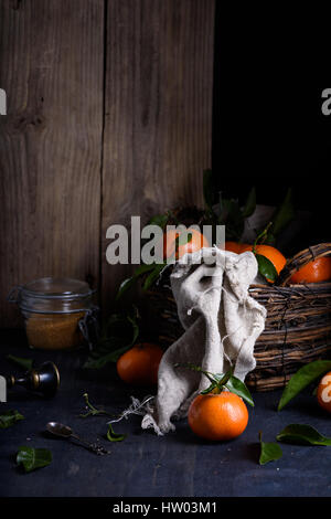 Fresh sweet orange fruits. Garden mandarines with leaves, dark background. Close up, selective focus. Stock Photo