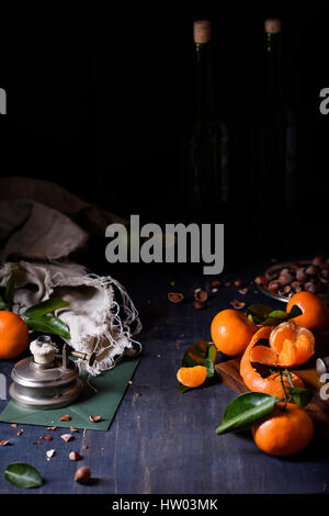 Fresh orange fruits with hazelnuts, dark background, close up. Stock Photo