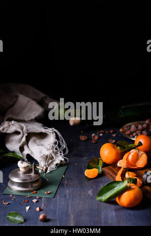 Fresh orange fruits with hazelnuts, dark background, close up. Stock Photo