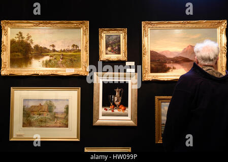 London, UK. 15th Mar, 2017. A visitor views paintings of display at The Chelsea Antiques Fair which opened at the Chelsea Old Town Hall today. The fair runs from 15 to 19 March. Credit: Stephen Chung/Alamy Live News Stock Photo