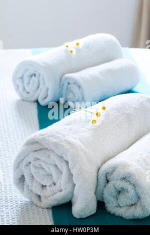 Rolled white towels on bed with flowers Stock Photo