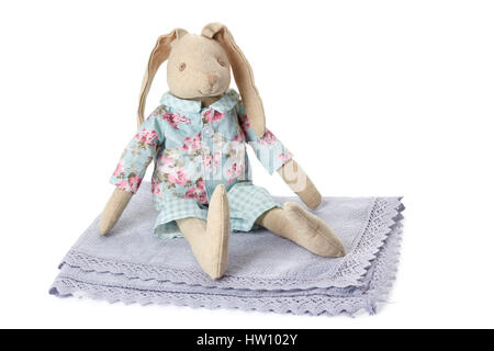 Soft bunny toy sitting on textile napkin over white Stock Photo