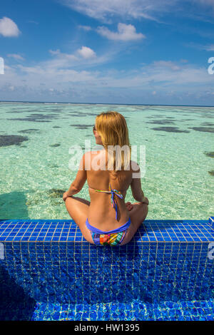 Maldives, Rangali Island. Conrad Hilton Resort. Woman in pool with view of the ocean and the back deck of the water villa. Stock Photo