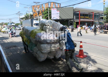 Local people are crossing Cambodia Thailand border with wooden wagons, filled with stuff in a plastic bags. Stock Photo