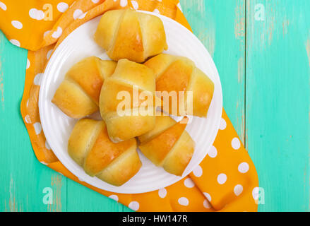 Freshly baked small buns on a white plate. Sausage in the dough. The top view Stock Photo