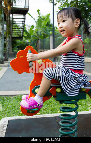 Asian Chinese little girl riding trojan horse at park Stock Photo