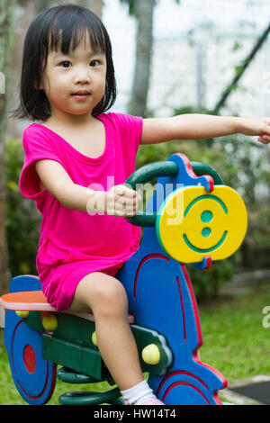 Asian Chinese little girl riding trojan horse at park Stock Photo