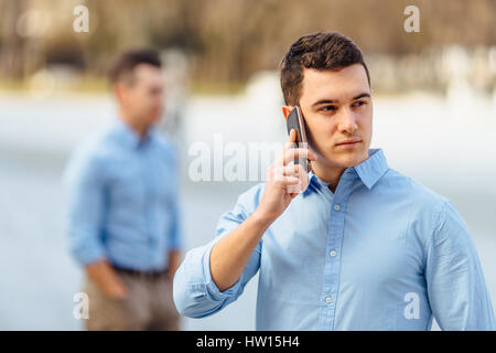 Businessman talking at his phone with friend on blur background Stock Photo