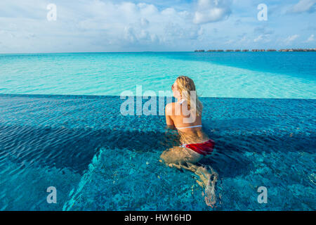 Maldives, Rangali Island. Conrad Hilton Resort. Woman in an infinity pool on the ocean. (MR) Stock Photo