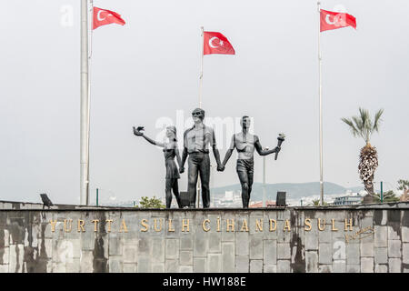 Monument of Ataturk and Youth signifying peace and hope, Kusadasi, Turkey, with Turkish flags in the background. translation of wording: 'Peace at Hom Stock Photo