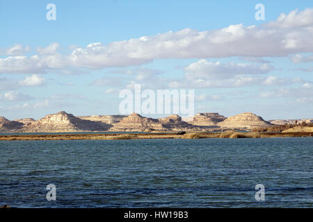 Rock and sand mountains hills heritage valley site on water lake with cloudy sky background in Siwa Oasis , Egypt tourism and nature Stock Photo