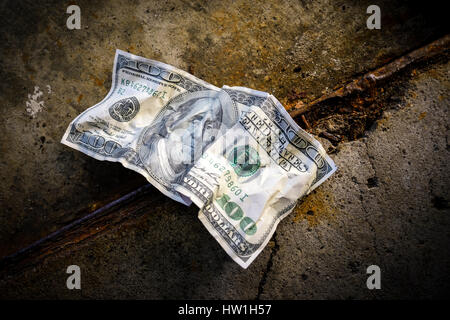 United States one hundred dollar bill on dirty ground Stock Photo