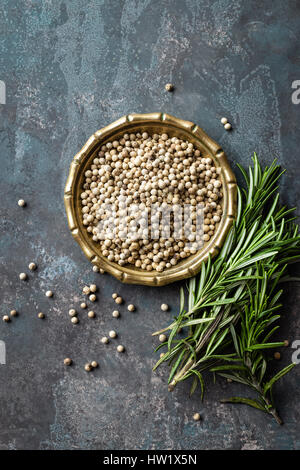 White pepper and fresh rosemary twigs, culinary ingredients on dark background, copy space Stock Photo