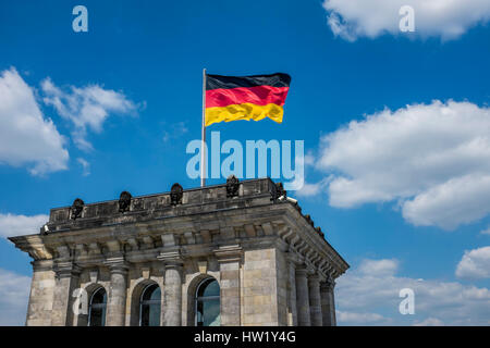 The flag of Germany, a tricolour, is waving in the wind on top of the Reichstag Building, the German parliament building, also known as the German Bun Stock Photo