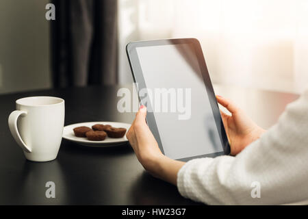 woman sitting by the the table at home and using digital e-book reader Stock Photo
