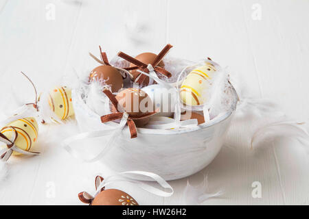 Easter eggs decorated with bows and feathers in wooden bowl Stock Photo