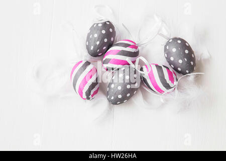 Pink and gray Easter eggs decorated with feathers on white background Stock Photo