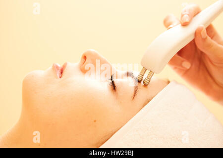 Cosmetology. Beautiful Woman At Spa Clinic Receiving Stimulating Electric Facial Treatment From Therapist. Closeup Of Young Female Face During Microcurrent Therapy. Beauty Treatment. Stock Photo