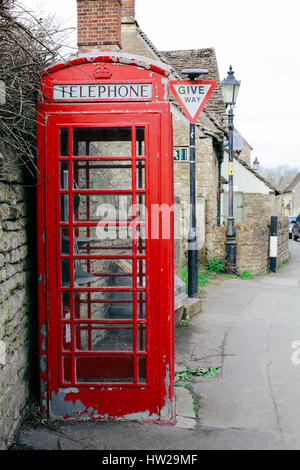 Old red telephone box with paint peeling off in a small English village Stock Photo