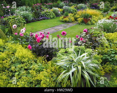 Chenies Manor Sunken garden in late July with lawn, path and vibrantly coloured pink dahlias, shades of green foliage and ornamental pond facing west. Stock Photo