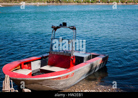 Weathered metal boat with red paint in water. Stock Photo