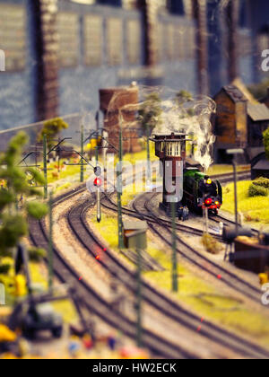 A model train going through a miniature setup with steam. Stock Photo