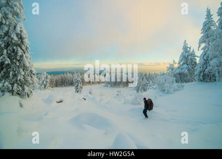 Caucasian man hiking in snowy forest at sunset