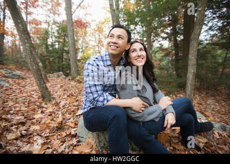 Couple sitting on rock in forest during autumn Stock Photo
