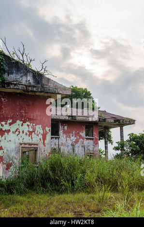 Ruined mansion surrounded by lush green with dramatic sky. Traces of the civil war in Robertsport, Liberia Stock Photo