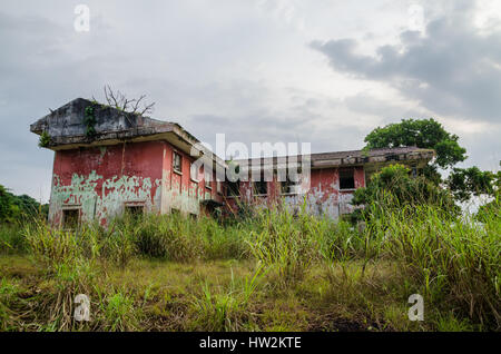 Ruined mansion surrounded by lush green with dramatic sky. Traces of the civil war in Robertsport, Liberia Stock Photo