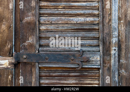 Details of weathered wooden door with old fashioned metal hinge Stock Photo