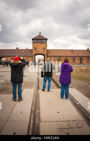Visitors and tourists taking photographs at the entrance to Auschwitz Birkenau concentration death camp Poland Stock Photo