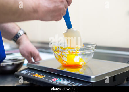 Man weighs caramel in a glass bowl on an electronic balance Stock Photo