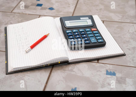 notebook in mathematics with handwriten exercise and a pencil and black calculator on ceramic surface desk Stock Photo