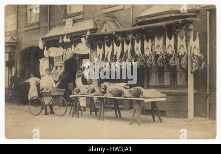 Original Edwardian era postcard of butcher's shop displays, displaying meat -  beef hanging outside, with men - staff / assistant / assistants and delivery bicycle, Erdington, Birmingham, England, U.K. circa 1905 Stock Photo